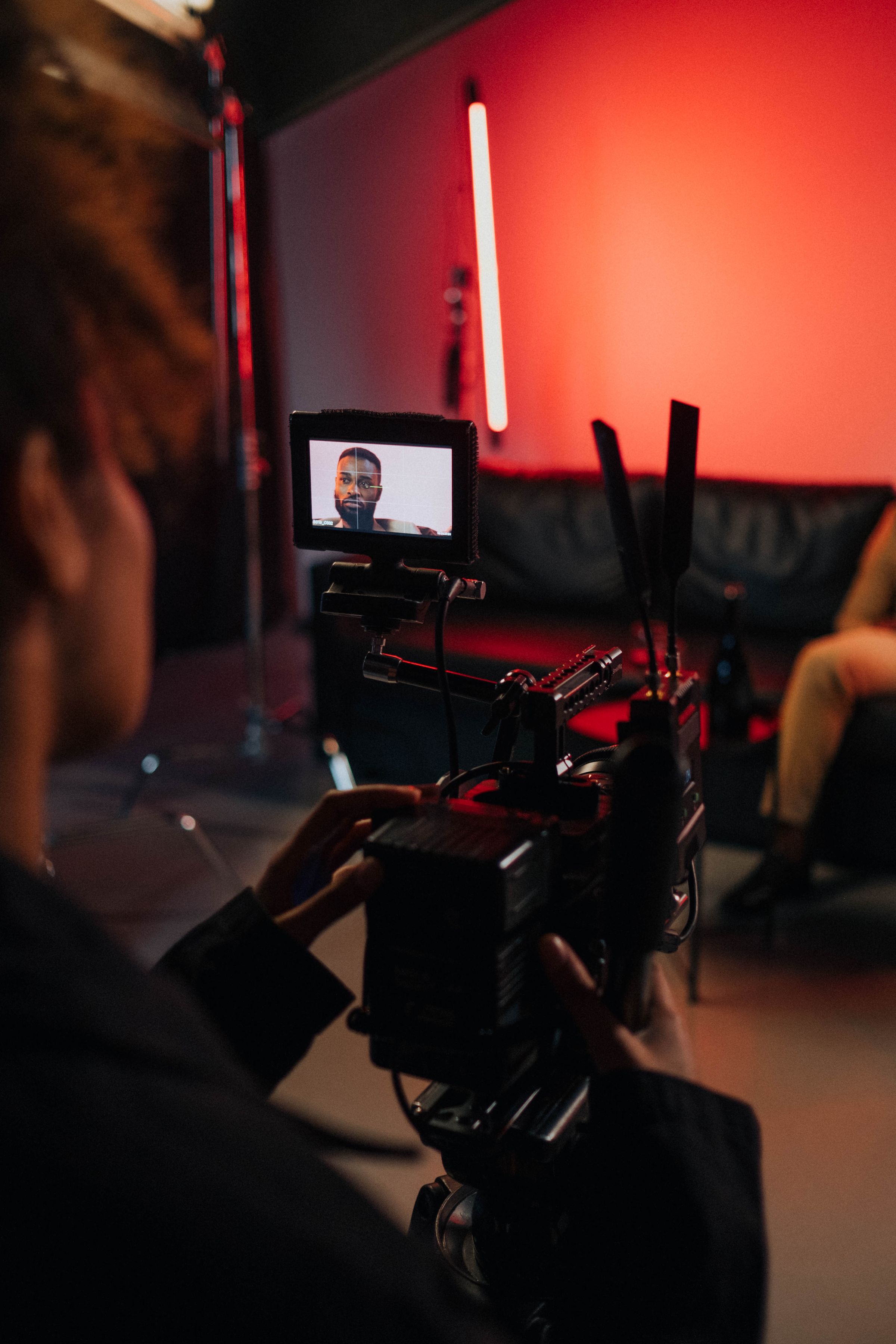 A cinematographer framing a performer through a professional cinema camera on set.