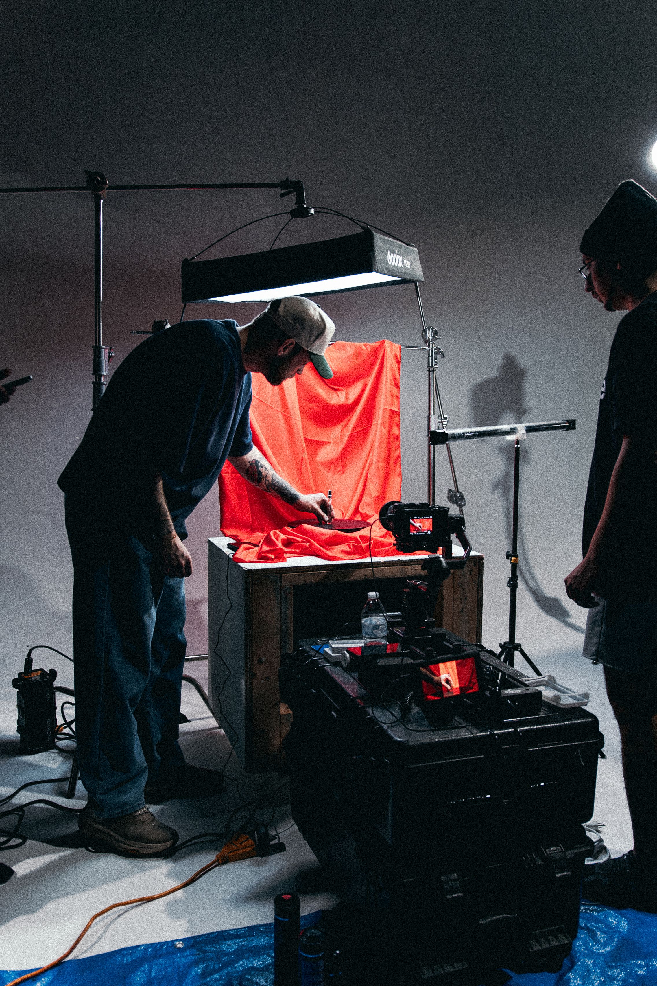 A film crew arranging lighting and set elements inside a working studio.